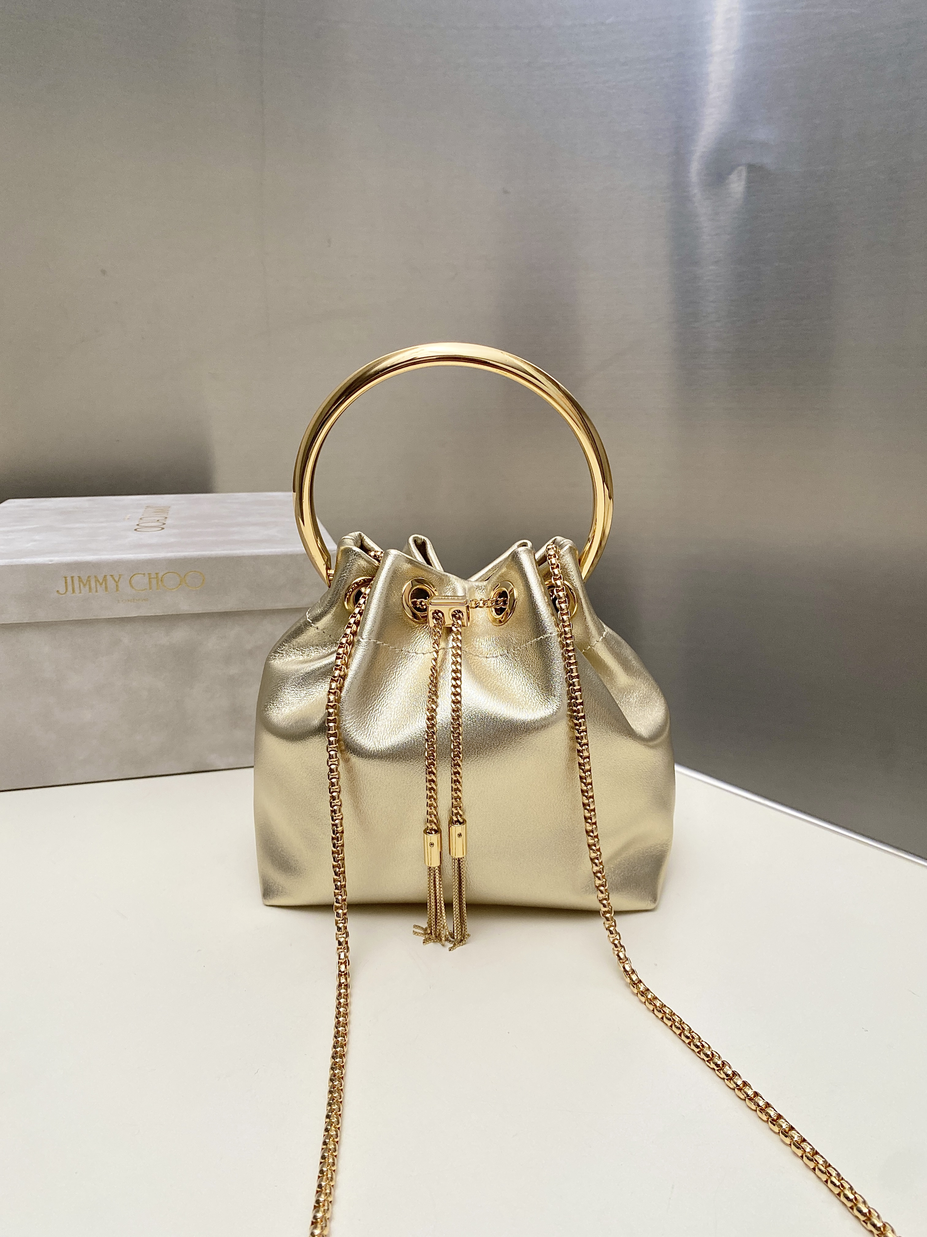 Bagsaaa J1m*y Ch00 Bon Bon Micro leather bucket bag in a gold metallic - 16cm